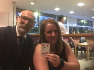 Woman holding a signed laying card accompanied by magician