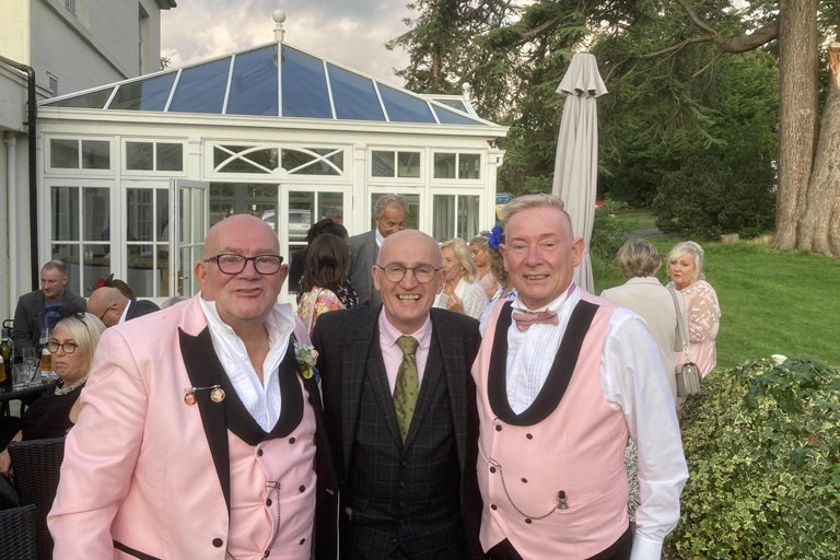 chester close up magician at same sex wedding. magician posing with two husbands.