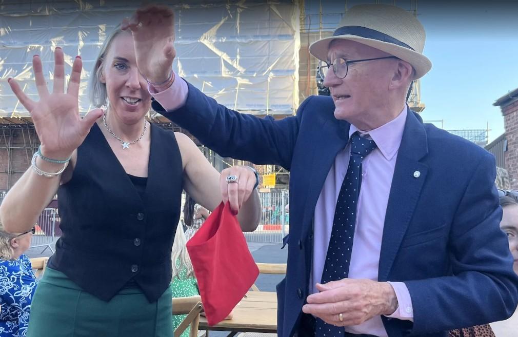 wedding magician in manchester and guest. The guest is holding an imaginary egg and is about top prodice a reall from an empty bag